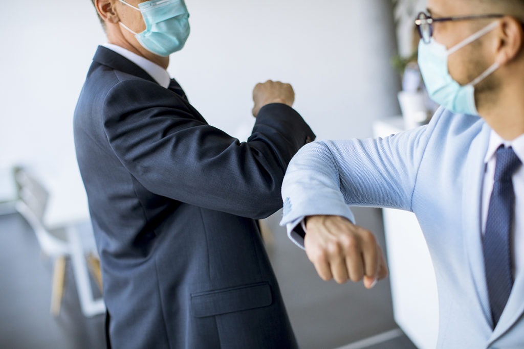 Two colleagues meeting in the office and greet with elbows bumping at vitafoods europe